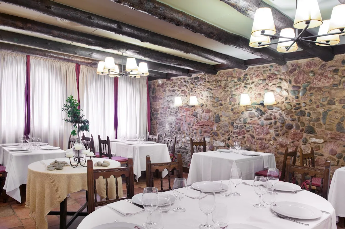 menjador-la-cuina-2026 Comedor La Cuina de Cal Pupinet, con mesas preparadas, paredes de piedra y vigas de madera